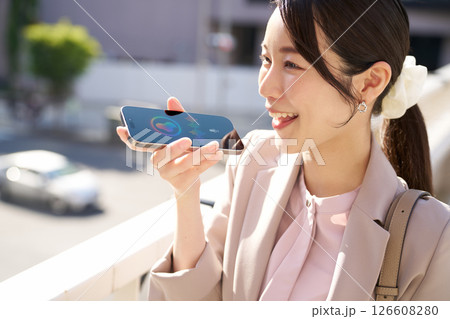 スマホの音声アシスタントと会話する笑顔の女性 126608280