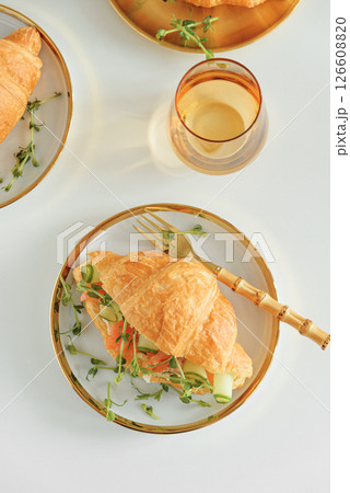 Croissant sandwich with salmon, onions and microgreens on white table. Healthy breakfast. Top view Croissant sandwich with salmon, onions and microgreens on white table. Healthy breakfast. Top view 126608820