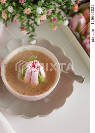 Hot chocolate in pink mug with whipped cream and tulip flower shaped marshmallows. Top view 126608823