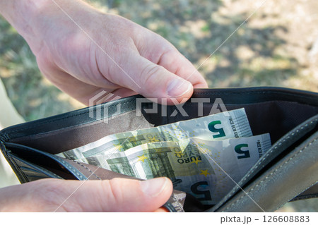 Man holding black leader partmone with bills in the hands. The wallet and money for commerce concept. 126608883