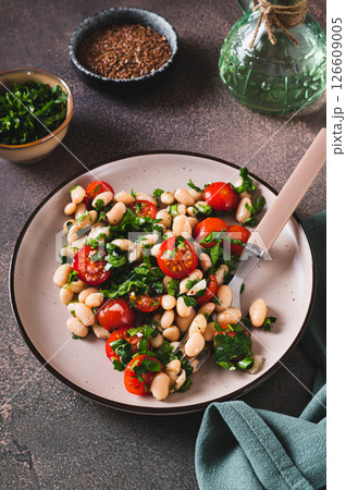 Vegetarian white bean, tomato and herb salad on a plate on the table vertical view Vegetarian white bean, tomato and herb salad on a plate on the table vertical view 126609005