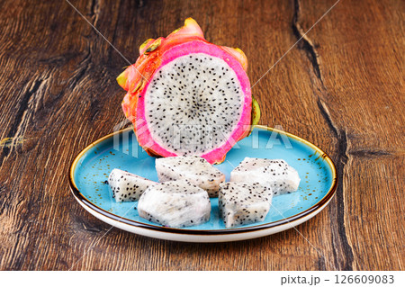 Half and sliced pieces of pitahaya pulp on a blue plate. Half and sliced pieces of pitahaya pulp on a blue plate. 126609083