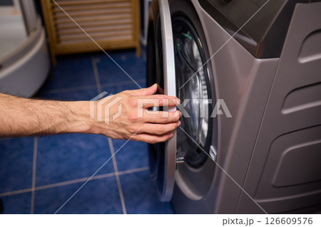 A contemporary modern washing machine with its door open, showcasing laundry inside 126609576