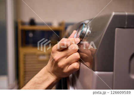 Individual Interacting with a Modern Washing Machines Control Panel for Efficient Laundry Tasks Individual Interacting with a Modern Washing Machines Control Panel for Efficient Laundry Tasks 126609589