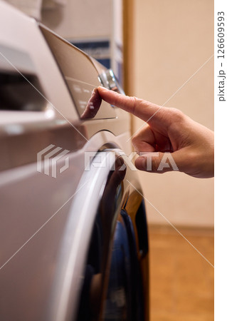 Individual Interacting with a Modern Washing Machines Control Panel for Efficient Laundry Tasks 126609593