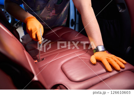 Cleaning a Luxury Car Seat with a Detail Brush and Foam for Maintaining Its Appearance 126610603