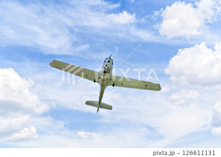 Single engine ultralight plane flying in the blue sky with white clouds	 126611131