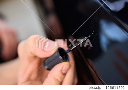 Using a specialized tool for meticulous detailing of the cars exterior surface area 126611201