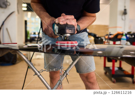 A professional technician expertly polishes glass surfaces in a workshop with precision 126611216