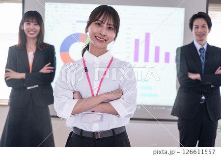 会議室のスクリーンの前で腕組しながら立つ男女 会議室のスクリーンの前で腕組しながら立つ男女 126611557