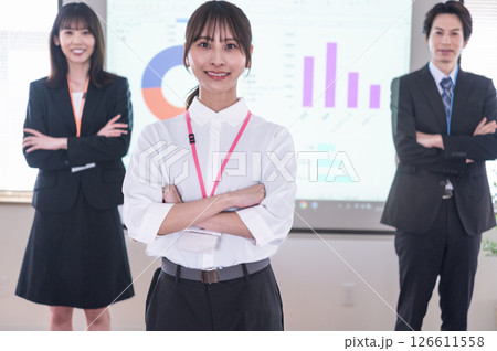 会議室のスクリーンの前で腕組しながら立つ男女 会議室のスクリーンの前で腕組しながら立つ男女 126611558