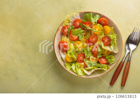 Fresh salad with lettuce, cherry red and yellow tomatoes, and arugula in a bowl top view, dieting and healthy eating, space for text 126613813