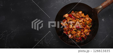 Traditional Chinese dish kung pao chicken in wok pan on dark background top view Traditional Chinese dish kung pao chicken in wok pan on dark background top view 126613835