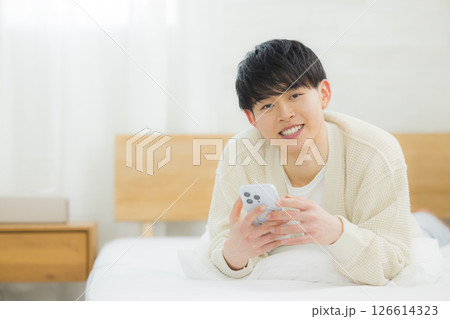 ベッドでスマホを使う若い男性 126614323