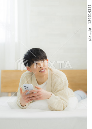 ベッドでスマホを使う若い男性 126614331
