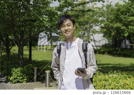 スマホを手にする新緑背景のミドルエイジの男性のポートレート 126615666