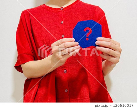 青いクエスチョンマークを持った赤い服を着た女性 126616017