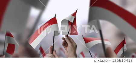 Indonesia flags in their hands on a blurred urban background Indonesia flags in their hands on a blurred urban background 126616418