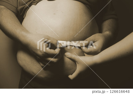 Asian fat man in front of a mirror looks at his body. Excess belly fat, Unhealthy lifestyle, Diet concept. 126616648