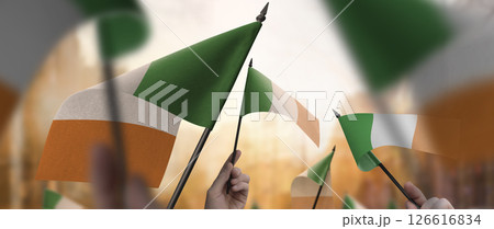 Ireland flags in their hands on a blurred urban background 126616834