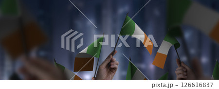 Ireland flags in their hands on a blurred urban background Ireland flags in their hands on a blurred urban background 126616837