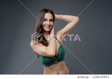 Belly dancer showcases graceful movements in elegant green costume 126616953