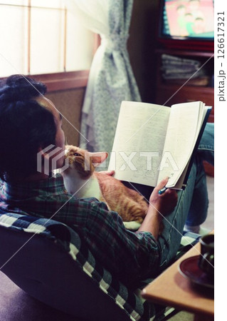 読書中の飼い主のおっちゃんに甘える茶虎の猫 126617321