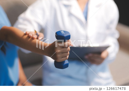 Unrecognizable uses blue hand weight during physical therapy session Unrecognizable uses blue hand weight during physical therapy session 126617478