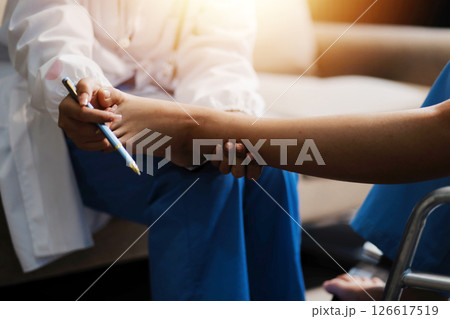 A female doctor examines an elderly patient with knee pain due to arthritis. The patient is being assisted in recovery, focusing on pain management and improving mobility. 126617519