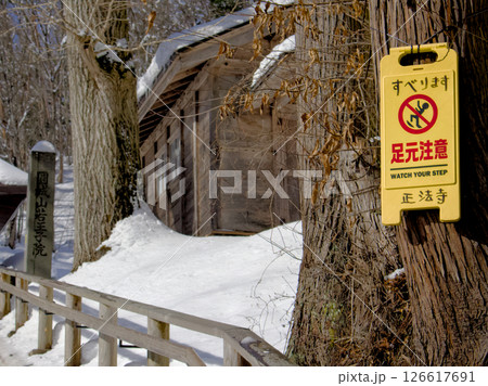 雪道の大木に足元注意の看板が設置されている風景 雪道の大木に足元注意の看板が設置されている風景 126617691