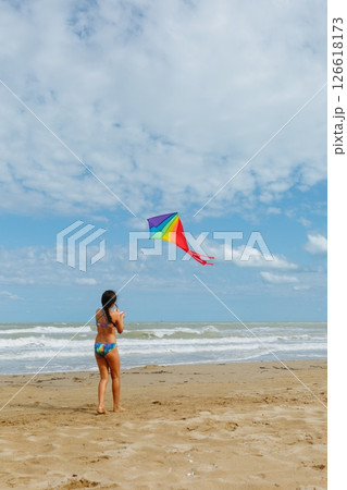 rear view of a girl flying a kite on the beach 126618173