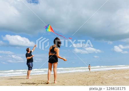 wide angle view of father and one daughter at the beach flying a kite 126618175