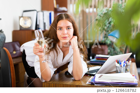 Charming businesswoman with a glass of wine posing in company office Charming businesswoman with a glass of wine posing in company office 126618782