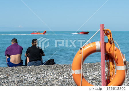 Orange lifebuoy on the seashore guarding vacationers. Orange lifebuoy on the seashore guarding vacationers. 126618802