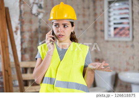 Portrait of young woman builder having telephone conversation 126618875