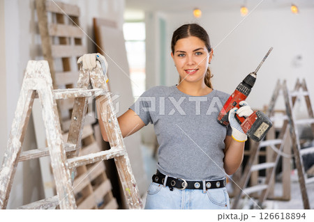 Woman with a screwdriver in her hands in a renovated room 126618894