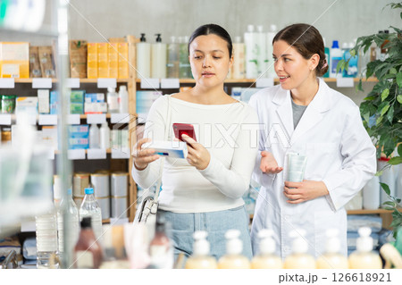 Woman scanning ointment while pharmacist offering friendly support Woman scanning ointment while pharmacist offering friendly support 126618921