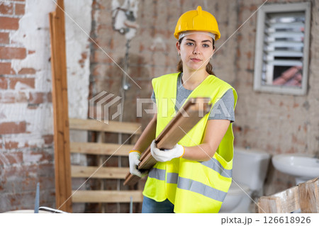Young woman construction worker carrying wooden plank 126618926