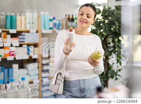 Middle-aged woman choosing shampoo or gel in drugstore 126618984
