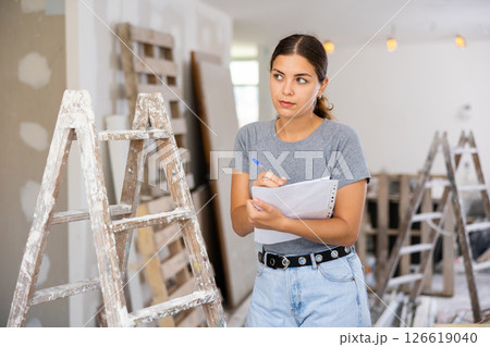 Female architect matching check list during repair works 126619040