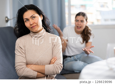 Upset woman sitting at home while girl calming her, asking to forgive after argument Upset woman sitting at home while girl calming her, asking to forgive after argument 126619096