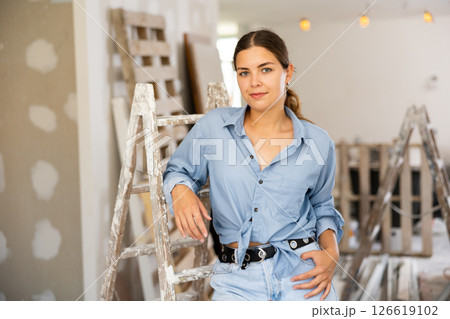 Portrait of positive young woman next to a stepladder in renovated room Portrait of positive young woman next to a stepladder in renovated room 126619102