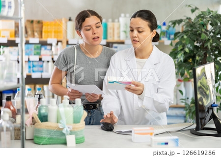 Pharmacist recommending medicines to woman at drugstore counter 126619286