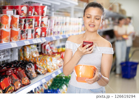 Woman scans qr code with smartphone on label of traditional chinese noodles in supermarket Woman scans qr code with smartphone on label of traditional chinese noodles in supermarket 126619294