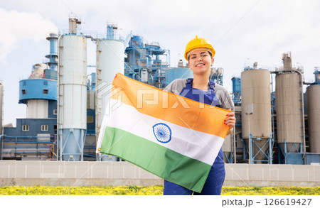 National flag of India in the hands of girl in overalls against background of modern metallurgical plant National flag of India in the hands of girl in overalls against background of modern metallurgical plant 126619427