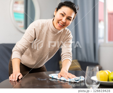 Woman cleaning table with rag at home 126619428