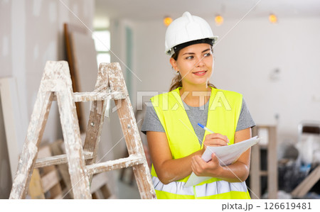 Positive woman builder checking project documentation Positive woman builder checking project documentation 126619481