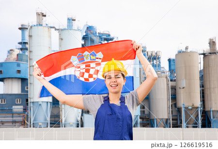 Happy woman waving flag of Croatia against the background of modern factory Happy woman waving flag of Croatia against the background of modern factory 126619516