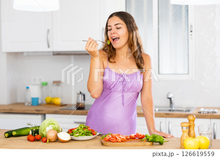 Portrait of housewife eating vegetable salad at table at home 126619559