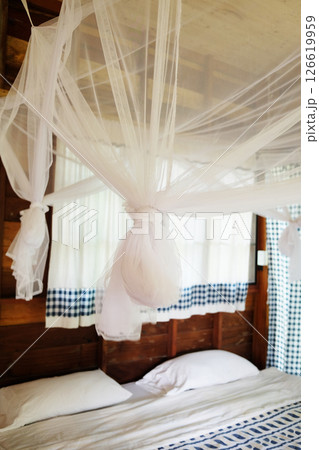 Close up Mosquito netting hanging around bed frame in vintage bedroom of Tradition wooden homestay in Thailand Close up Mosquito netting hanging around bed frame in vintage bedroom of Tradition wooden homestay in Thailand 126619959